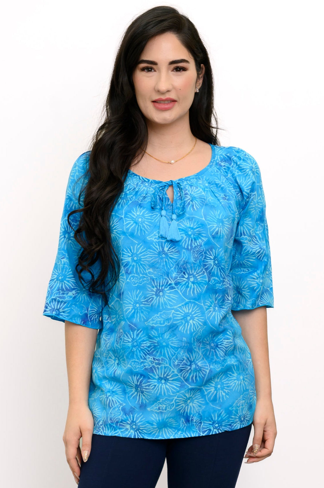Woman wearing a blue floral top and navy pants on a white background, front view