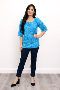 Woman wearing a blue floral top and navy pants on a white background, full body front view