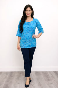 Woman wearing a blue floral top and navy pants on a white background, full body front view