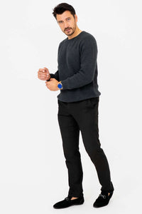 Man adjusting his sleeve in a charcoal crewneck sweater and black pants