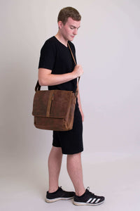 Man looking down carrying brown buffalo leather messenger bag, adjustable crossbody strap