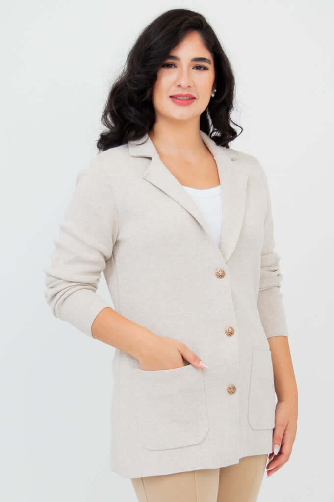 Front view of woman wearing the Margaret beige cotton cardigan with notched lapel and gold buttons