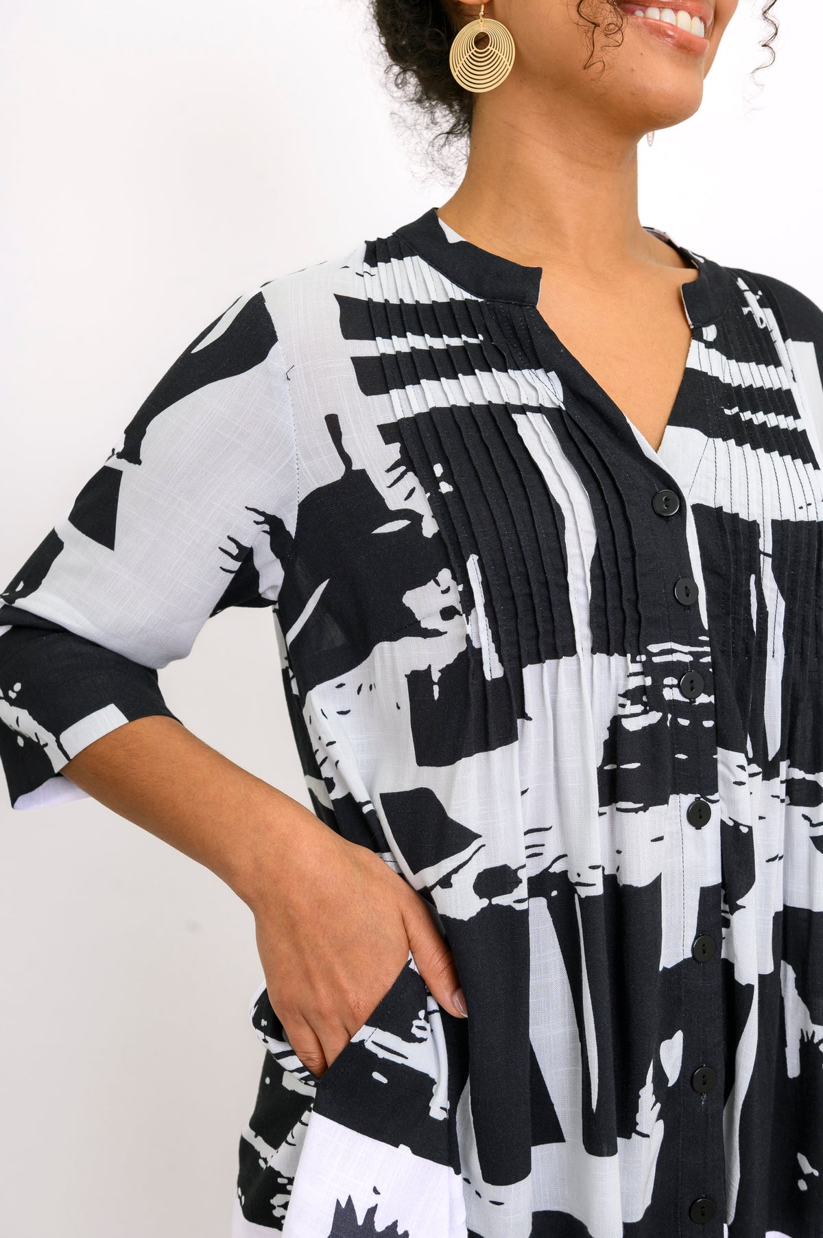 Close up of woman wearing a black and white patterned shirt with her hand in the shirt pocket