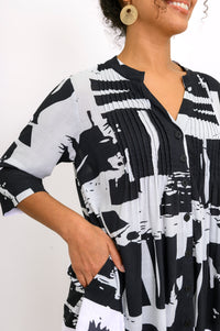 Close up of woman wearing a black and white patterned shirt with her hand in the shirt pocket
