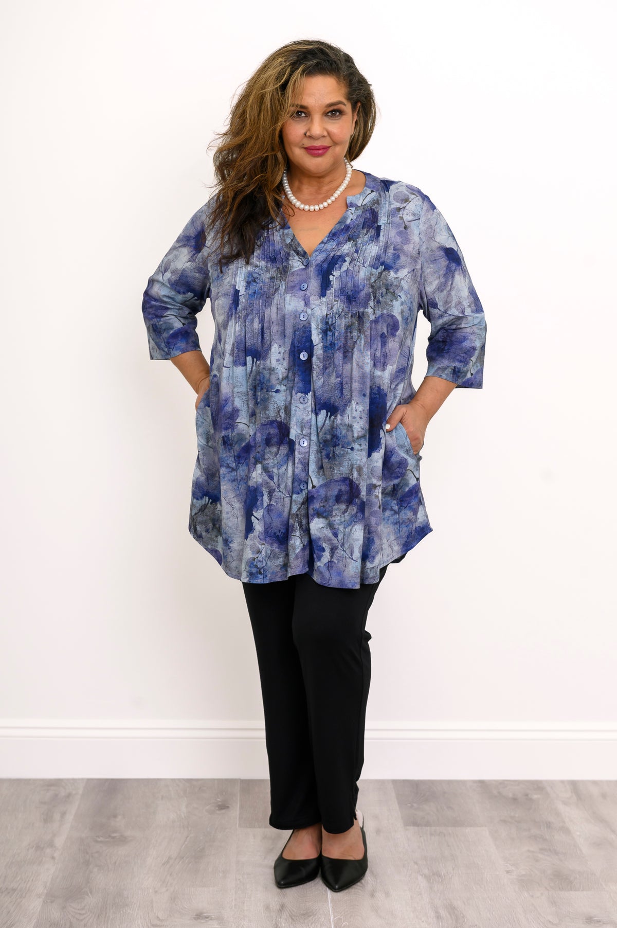 Wide studio shot of a loose-fit blue floral linen bamboo blend blouse with vertical pin-tucks.