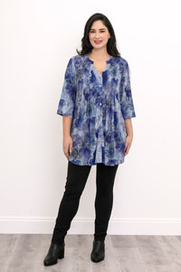 Full-length front view of a woman wearing a blue watercolor print tunic blouse with black leggings.
