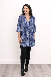 Full-length front view of a woman in a blue watercolor print tunic blouse with a mandarin collar and black leggings.