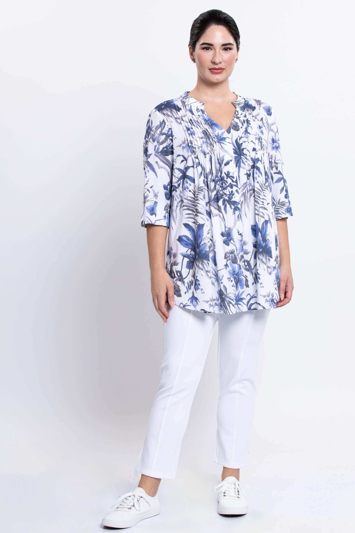 Full-body front view of woman in Margate blouse with blue floral print and white pants