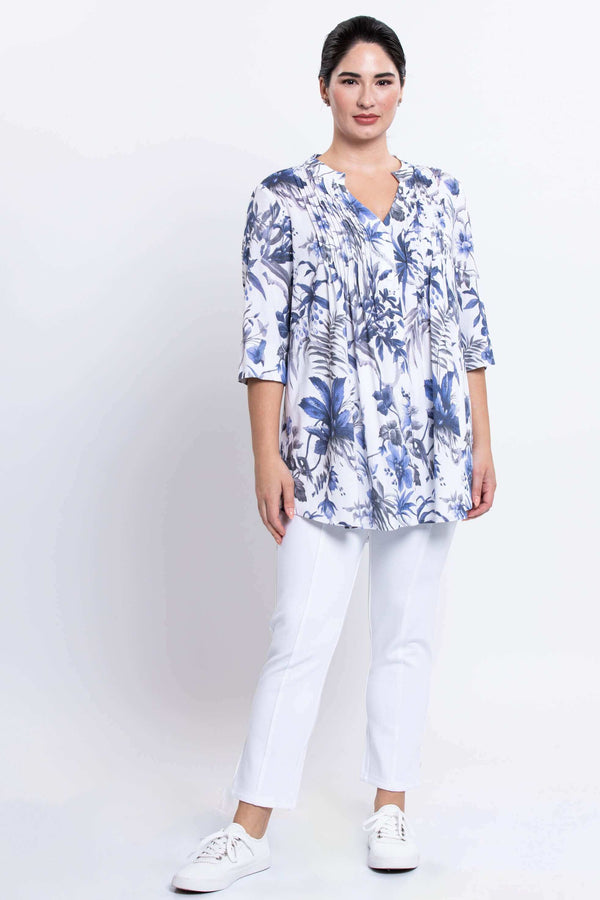 Full-body front view of woman in Margate blouse with blue floral print and white pants