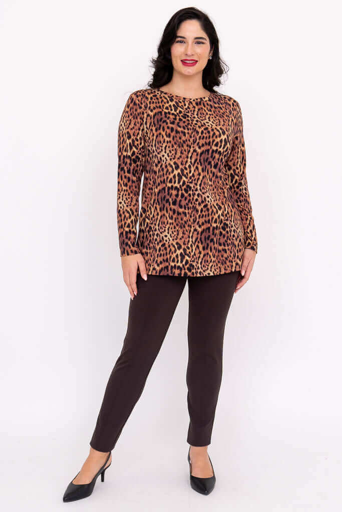 Woman in leopard print top and brown pants posing with one leg forward