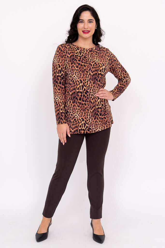 Woman wearing leopard print top with hand on hip, smiling