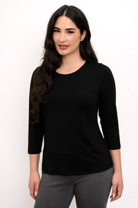 Front view of woman wearing round-neck black shirt and grey slim pants
