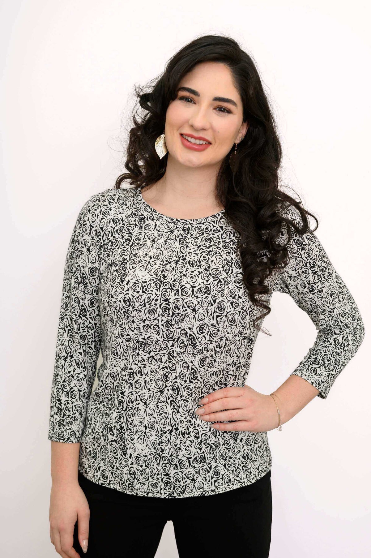 Smiling woman wearing black and white rose print tee, hand on hip