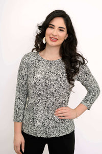 Smiling woman wearing black and white rose print tee, hand on hip