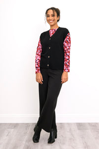 Side-angled view of an onyx knit vest over a pink floral shirt, highlighting the deep ribbed waistband.