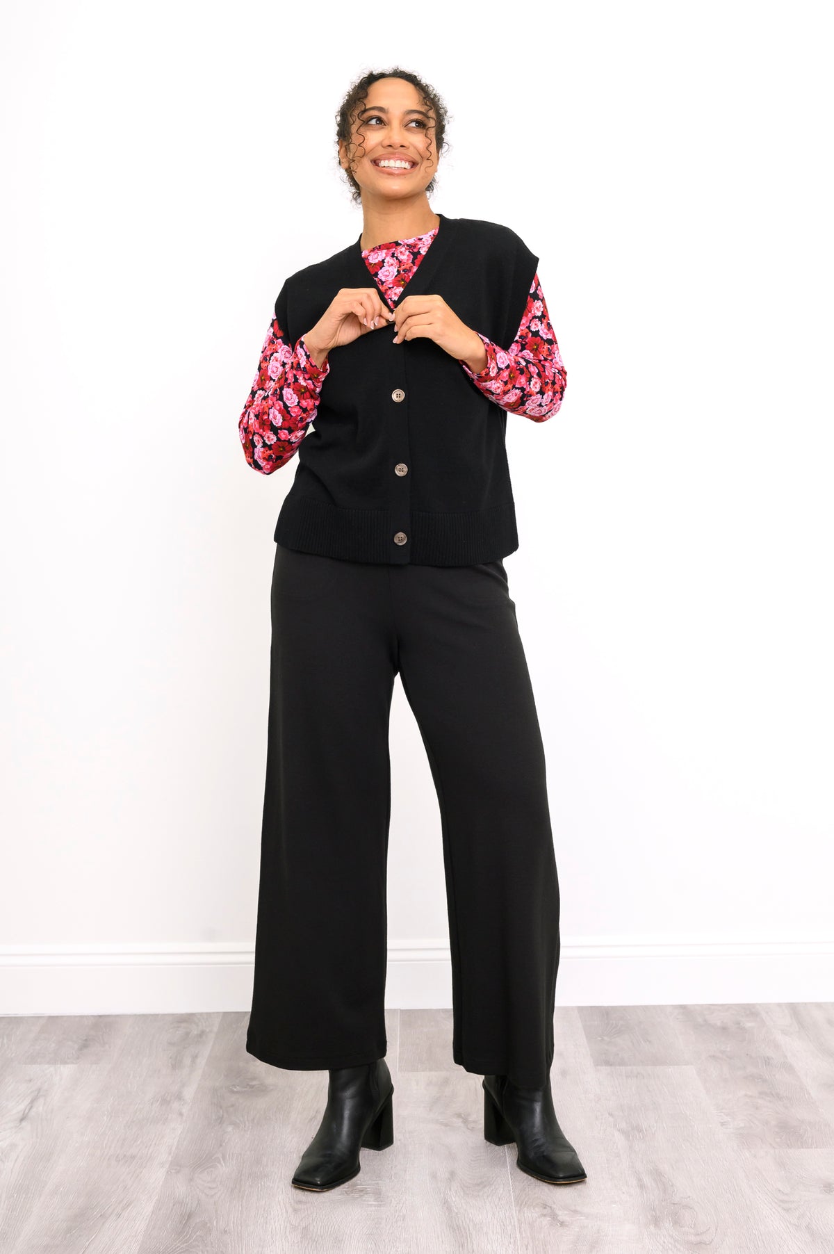 Front view of a women's black flat-knit layer with marled buttons, styled casually on a white background.