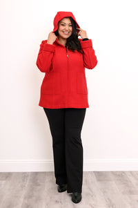 Woman wearing a bright red jacket unzipped and with the hood over her head
