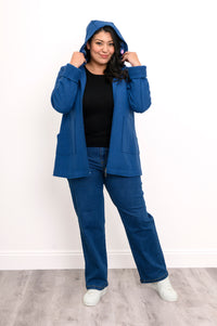 Woman wearing a cobalt blue jacket unzipped and with the hood over her head