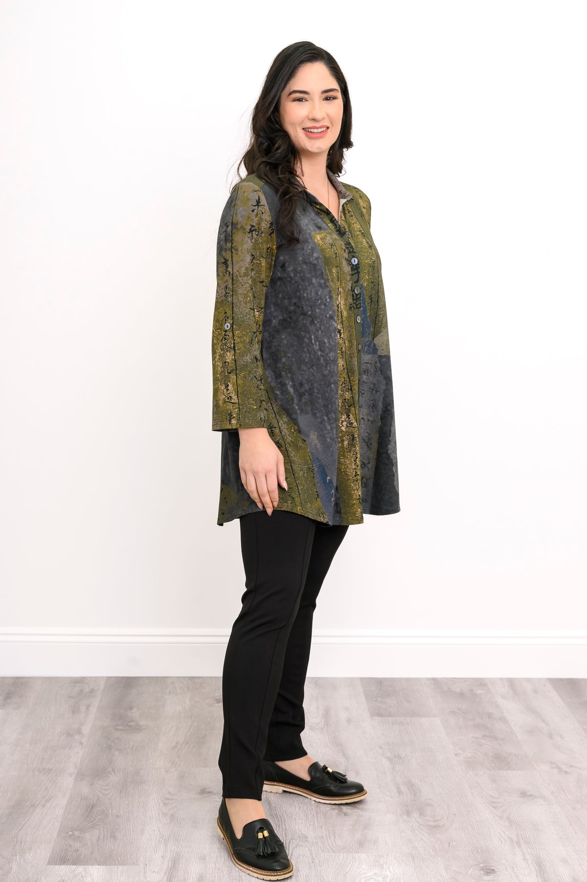 Angled view of a women's green longline knit shirt with adjustable tab sleeves and a classic collar.