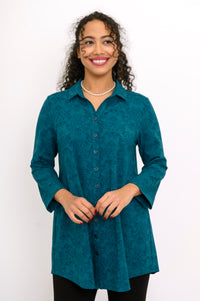 Teal patterned long-sleeve knit shirt buttoned up and accessorized with a pearl necklace, shown in a front view.