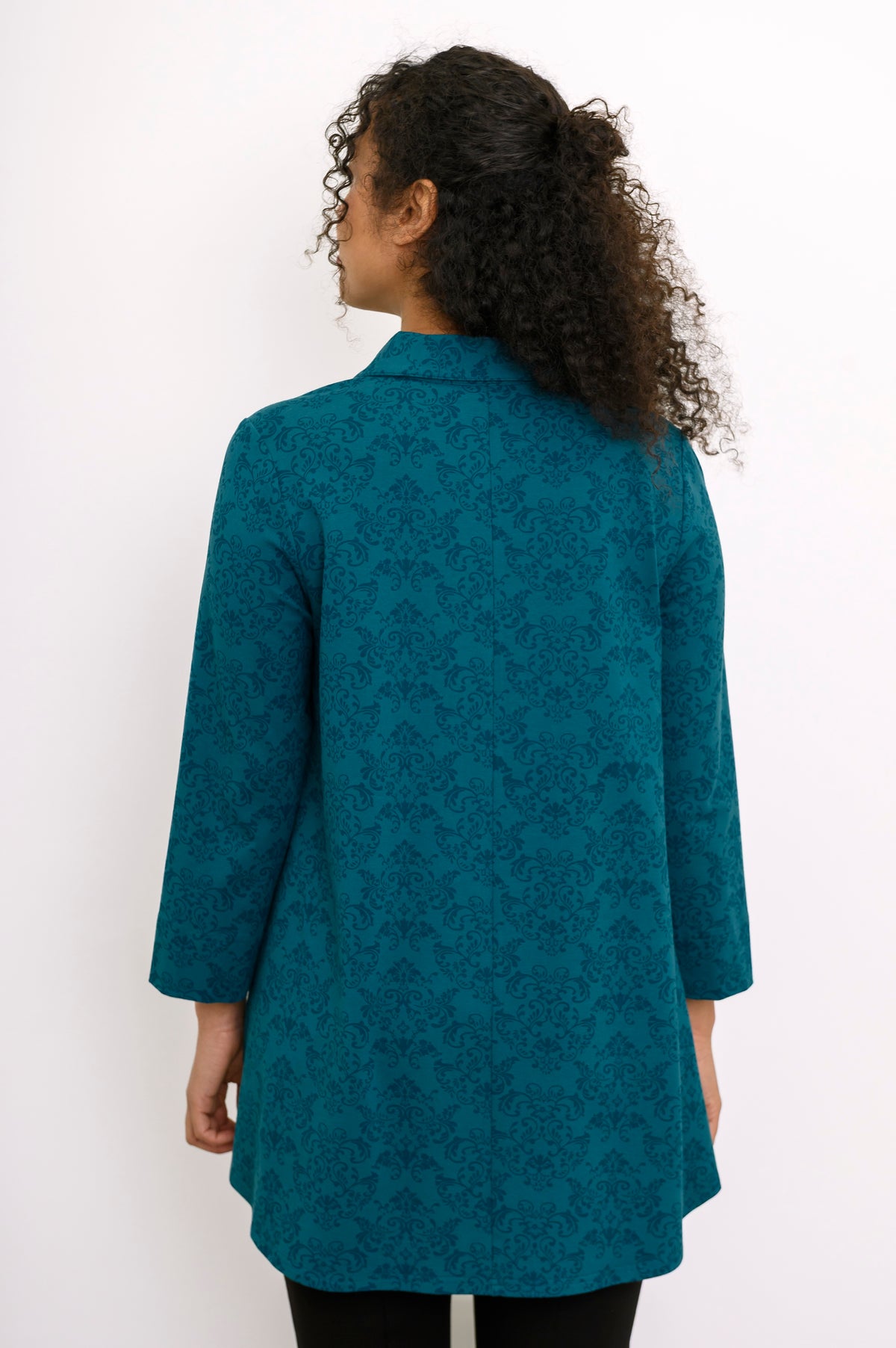 Rear view of a teal geometric print bamboo blouse, highlighting the shirt collar and comfortable hip-covering length.