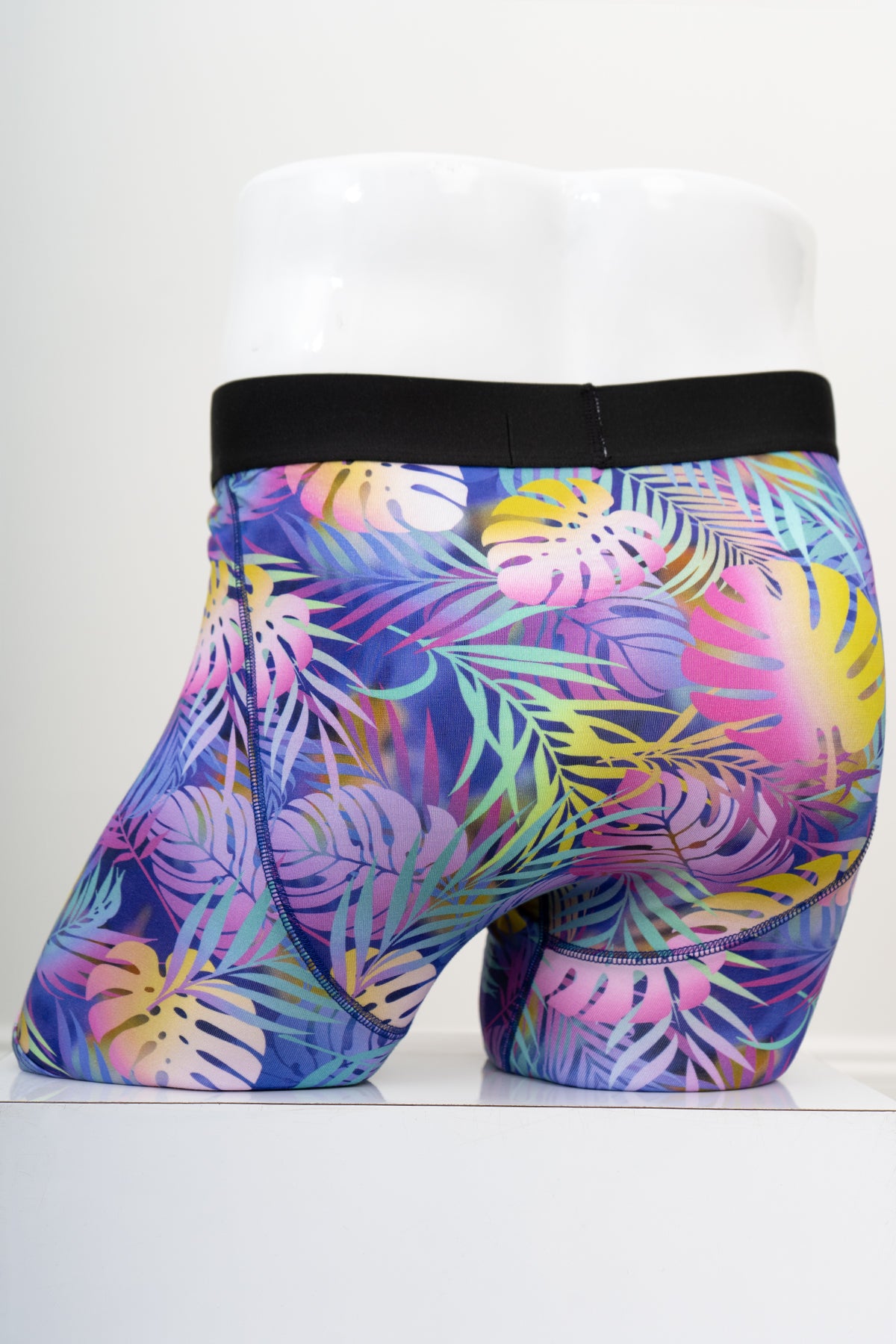 Back view of multicolour tropical leaf patterned men's underwear with an elastic waistband on a white background