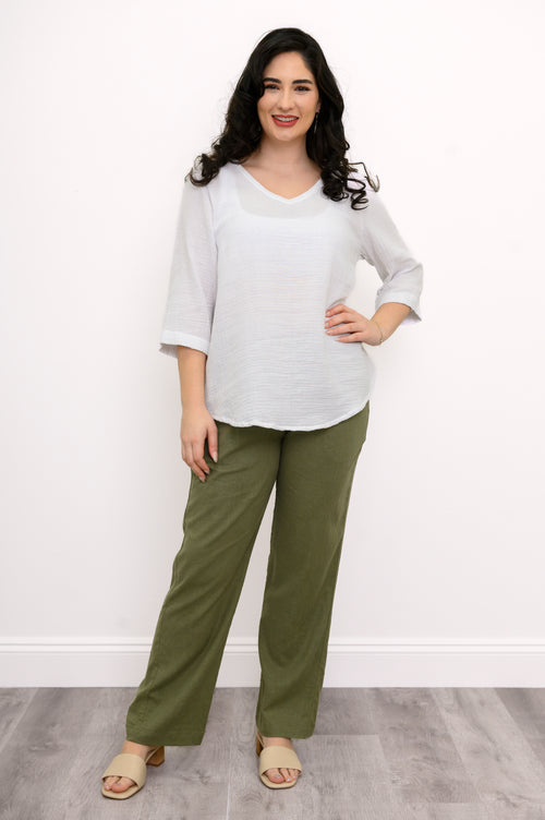 Woman wearing a white blouse, green pants, and beige shoes on a white background, front view