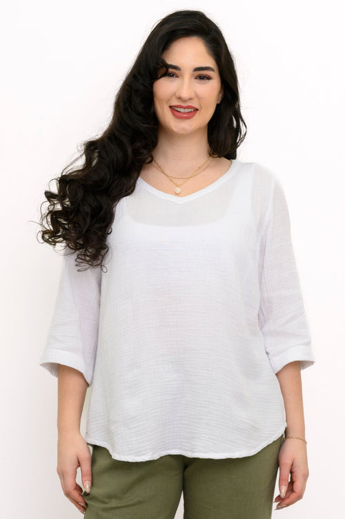 Woman wearing a white blouse and green pants on a white background, front view