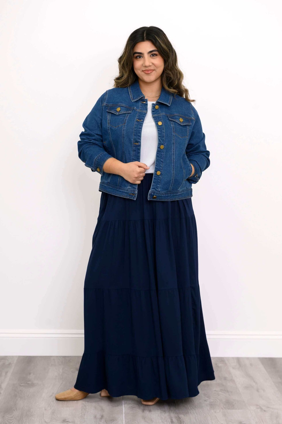 Model confidently posing in denim jacket and navy Roma tiered maxi skirt