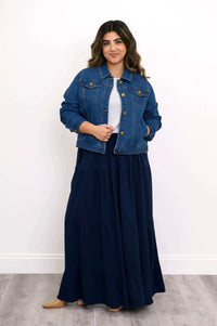 Model confidently posing in denim jacket and navy Roma tiered maxi skirt
