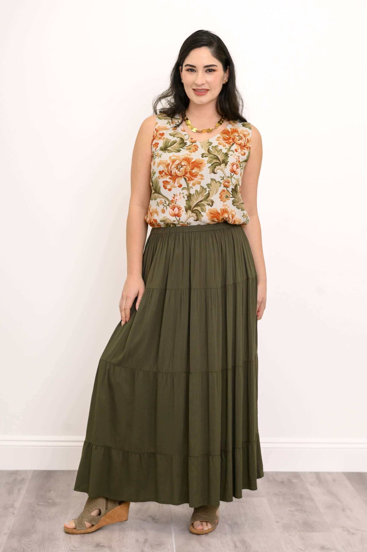 Model posing in an olive green tiered maxi skirt, holding the skirt to the side