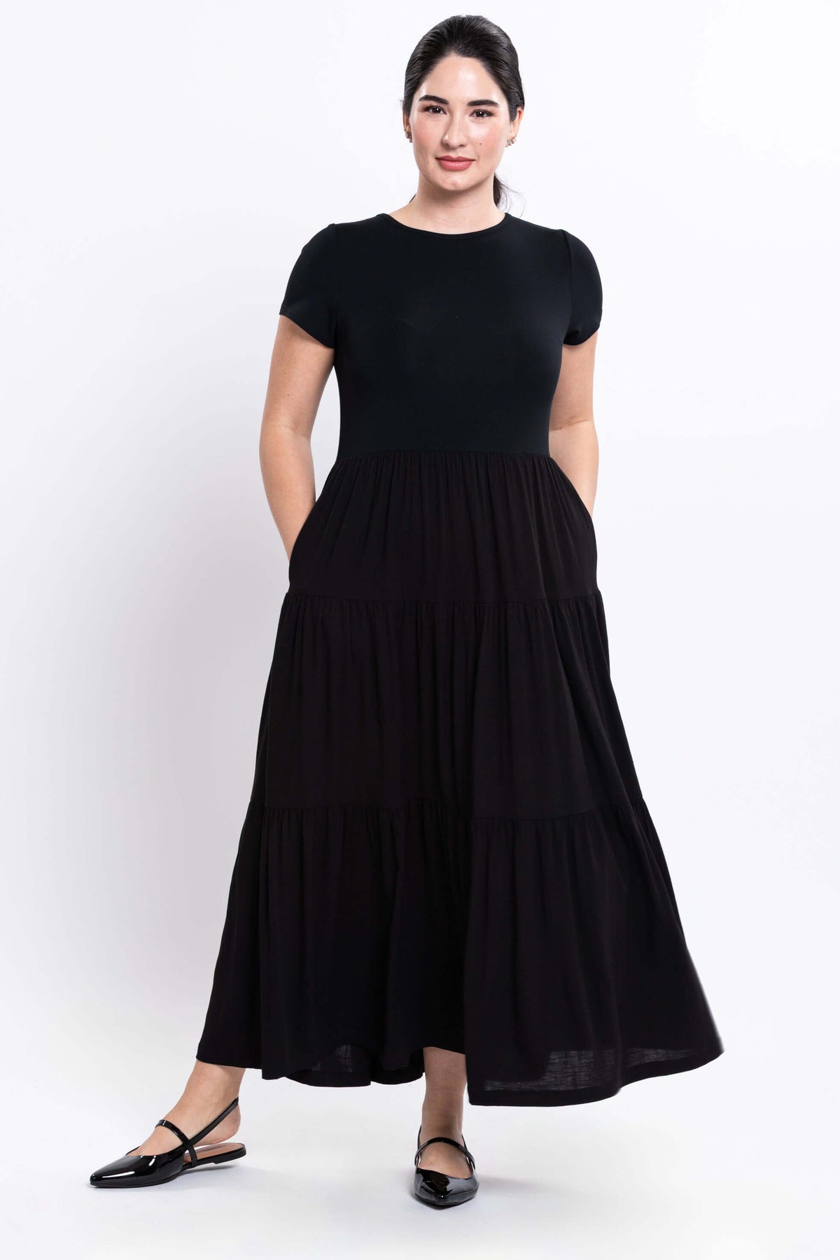 Woman showing pockets in a black empire waist maxi dress