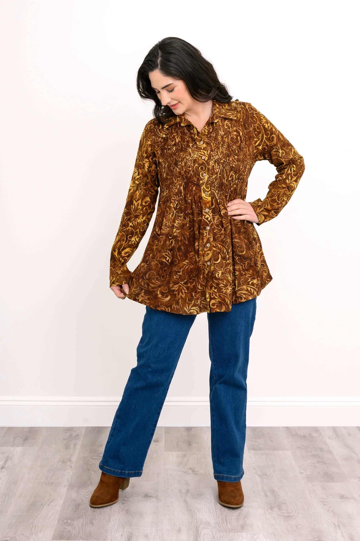 Model showing flare of brown floral smocked shirt paired with blue jeans and brown boots