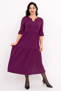 Woman lifting skirt of purple Bernadette dress to display ruffled tier and length