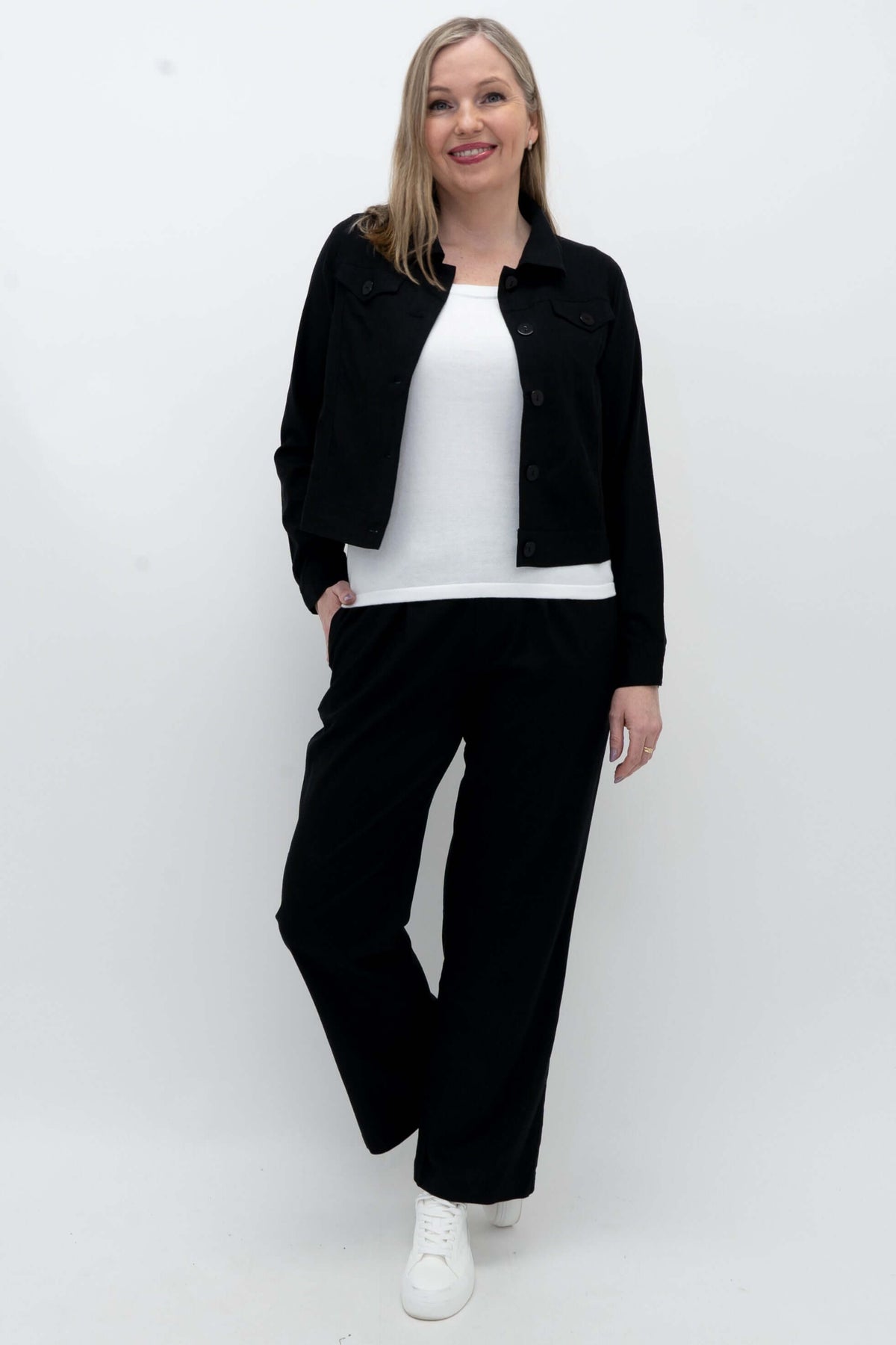 Model in black Melodie Pant, white sneakers, and black jacket, full body view