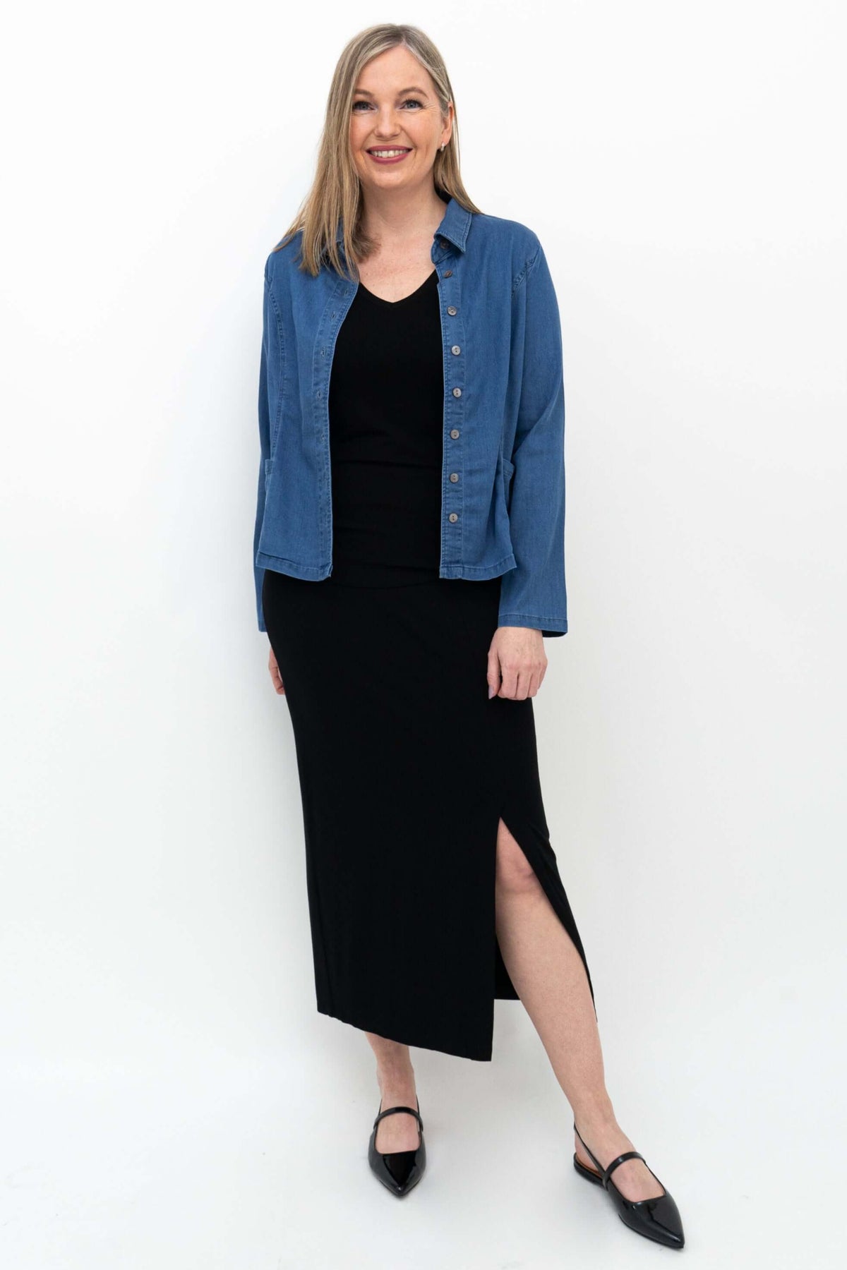 Woman wearing Eva slim black skirt and blue shirt, side stance