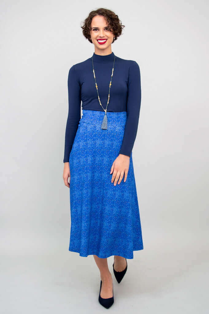 Full-length image of a smiling woman in a blue bamboo mid-calf skirt and dark top