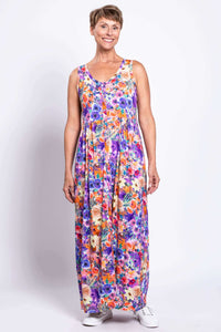 Woman in a vibrant floral sleeveless maxi dress, standing facing front with hand at side