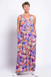 Woman wearing a sleeveless maxi dress with a colorful floral pattern and pockets, facing front