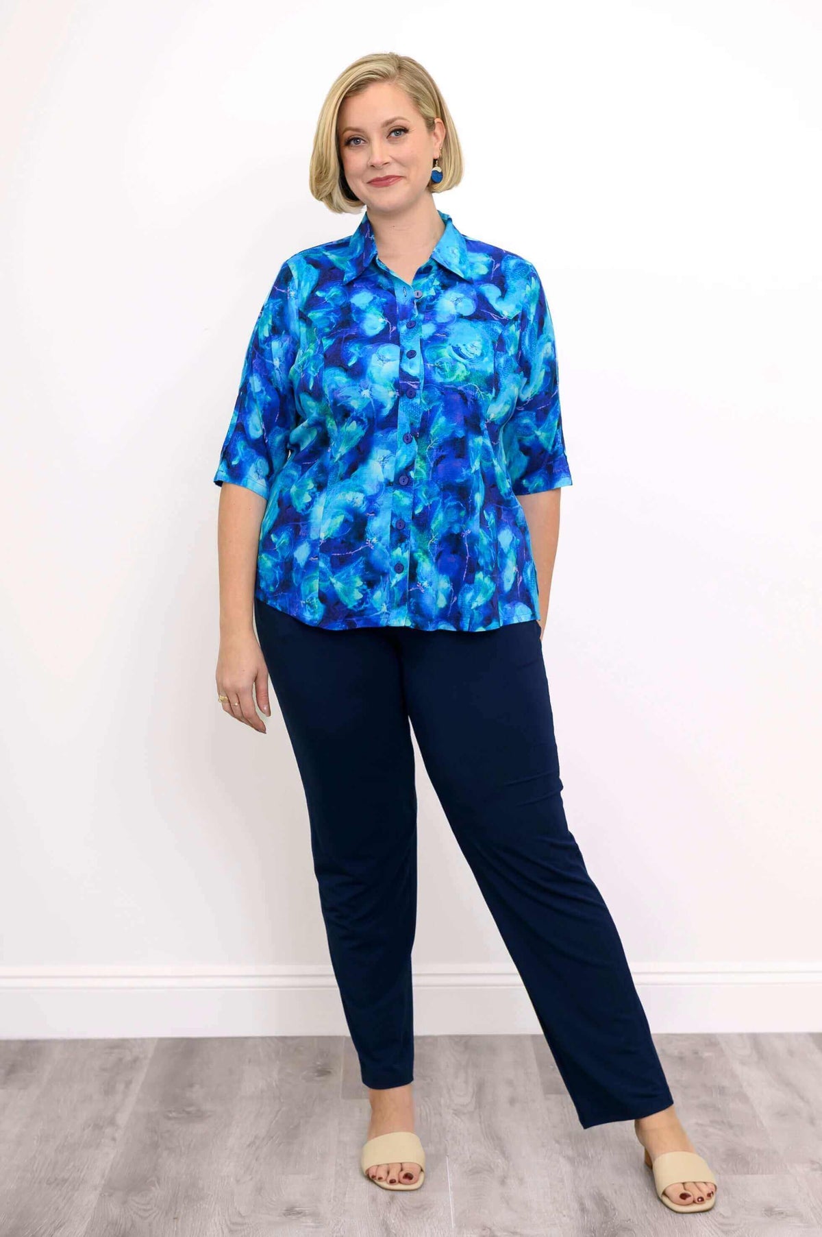 Model posing in Lorine blue bamboo-linen blouse with navy pants and sandals