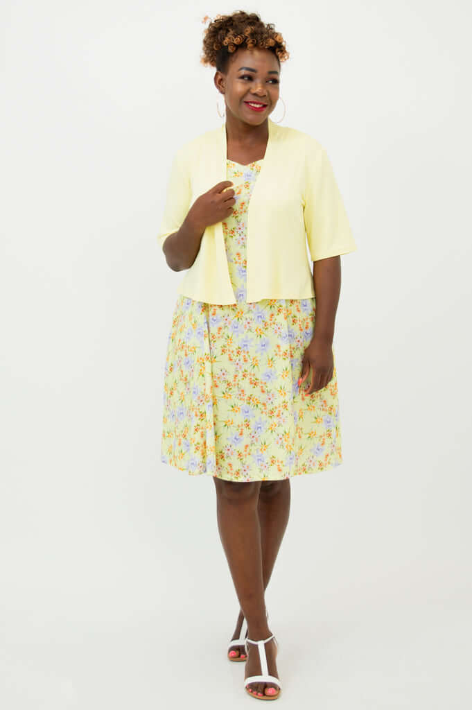 Woman modeling a yellow floral dress with a light yellow short-sleeve jacket