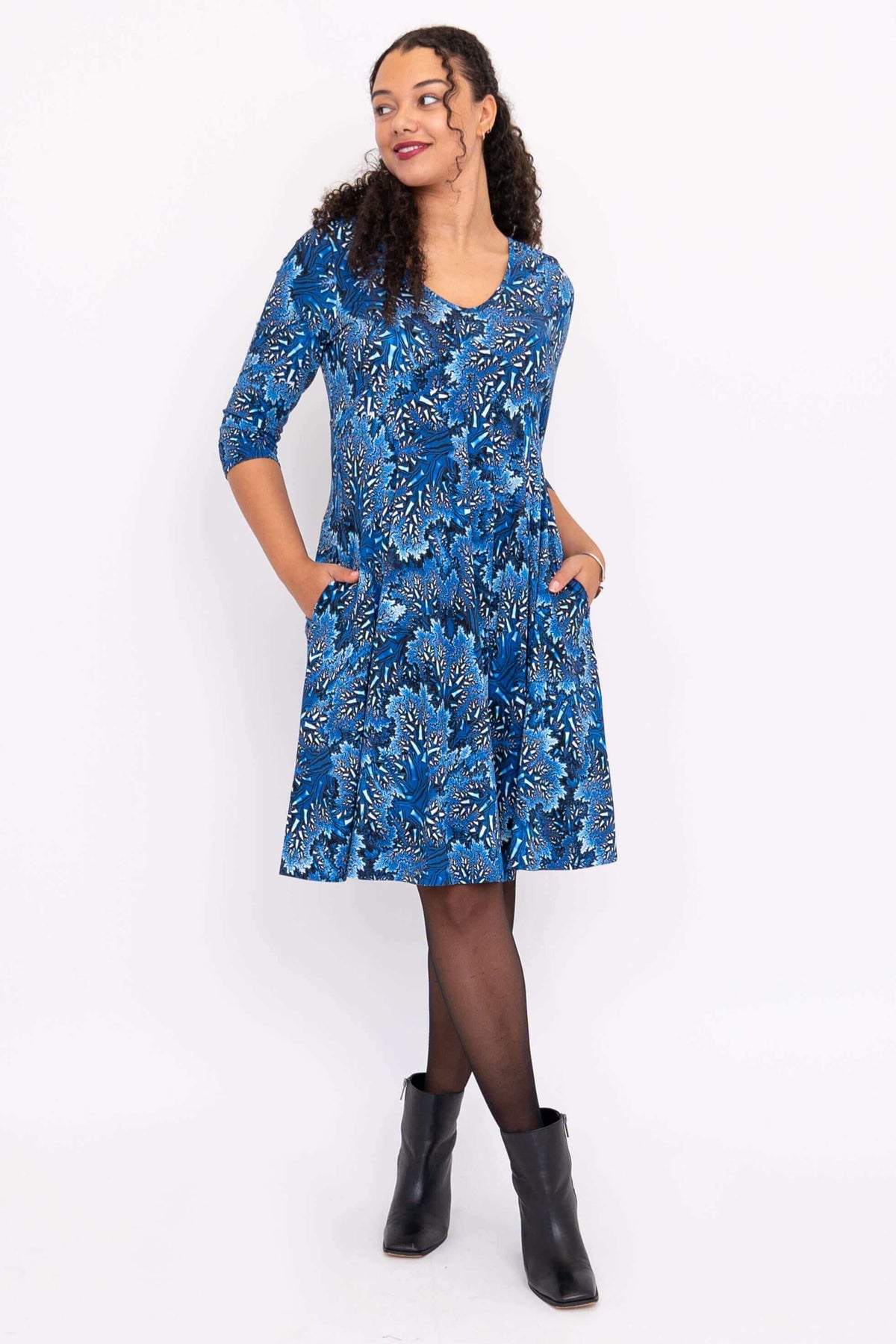 Model in blue fit and flare dress with pockets, looking sideways