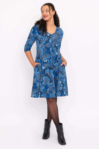 Model in blue fit and flare dress with pockets, looking sideways