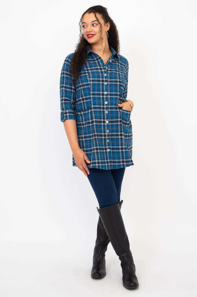 Woman modeling a blue plaid flannel tunic, wearing leggings and black boots