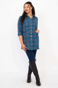 Woman modeling a blue plaid flannel tunic, wearing leggings and black boots