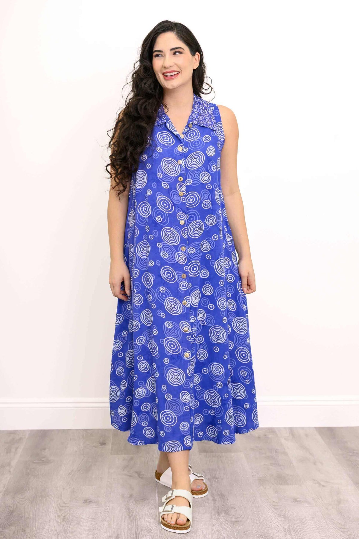 Model smiling in blue sleeveless dress with collared neckline and button front