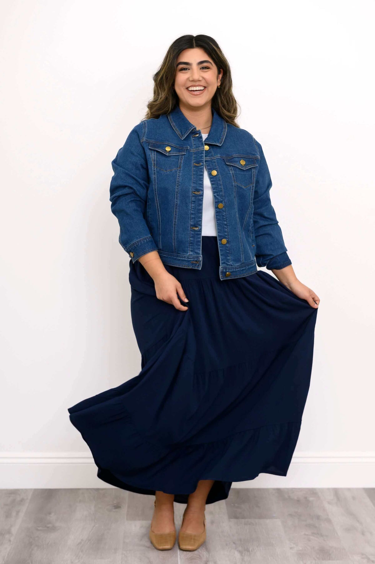Model in denim jacket swirling navy Roma tiered maxi skirt and smiling