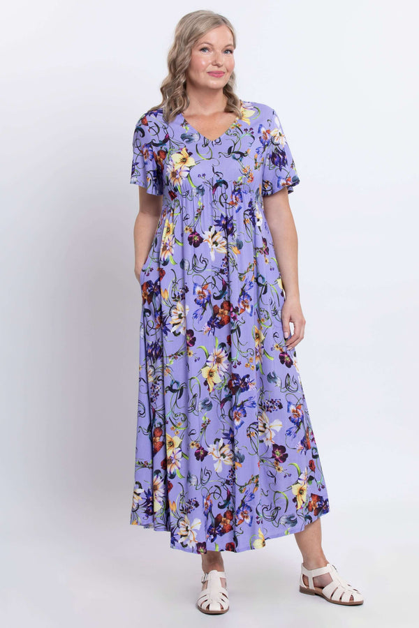 Woman posing in a lavender floral empire waist maxi dress with hands in pockets