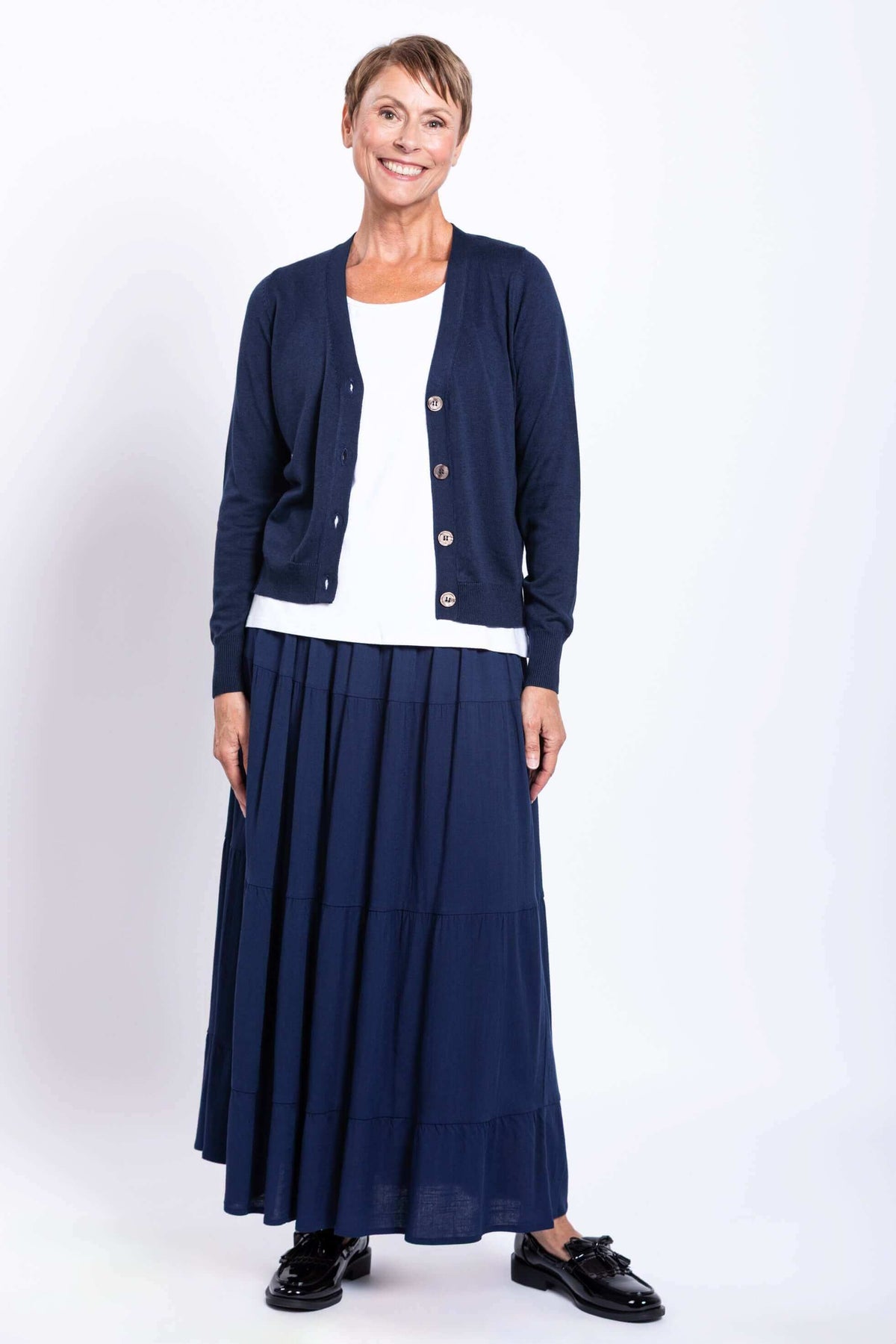 Model in navy Roma tiered maxi skirt and cardigan, standing and smiling