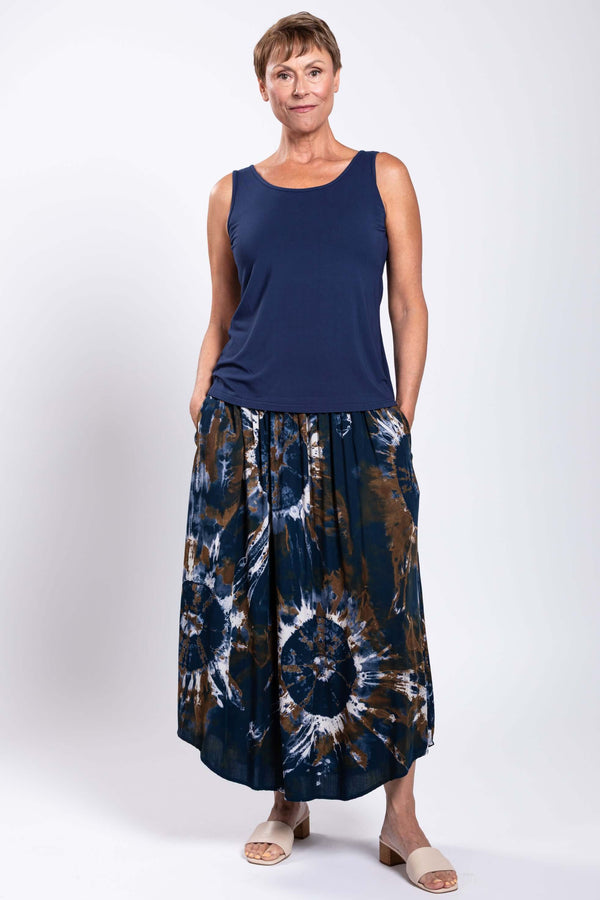 Model wearing navy sleeveless top and brown navy tie dye batik midi skirt, hands in pockets